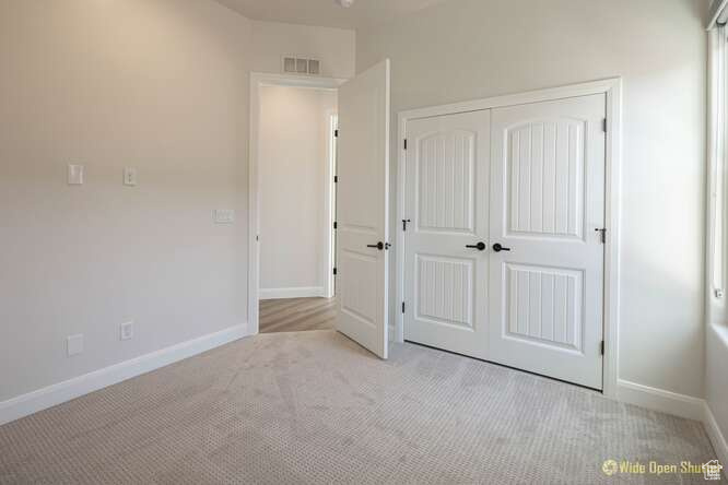 Unfurnished bedroom with light carpet, baseboards, and a closet