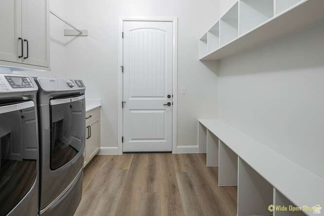 Laundry room with washer and dryer, cabinet space, light wood-type flooring, and baseboards
