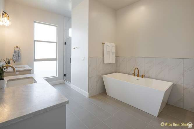 Full bathroom featuring a stall shower, a freestanding tub, tile walls, vanity, and tile patterned floors