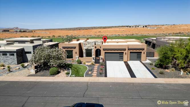 Pueblo revival-style home featuring an attached garage, stucco siding, and driveway