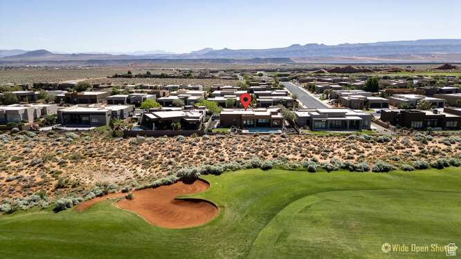 Aerial perspective of suburban area with a mountain backdrop and a local golf course