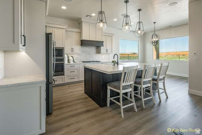 Kitchen with appliances with stainless steel finishes, decorative backsplash, baseboards, a kitchen bar, and wood finished floors