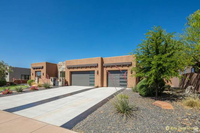 Adobe home featuring concrete driveway, stucco siding, and an attached garage