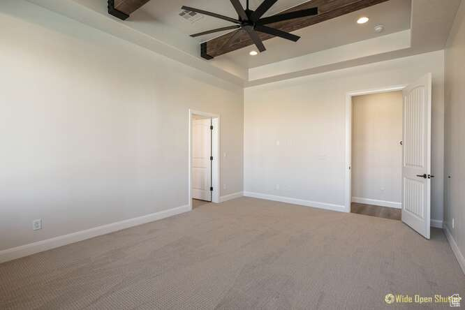 Unfurnished bedroom featuring carpet flooring, a tray ceiling, recessed lighting, baseboards, and ceiling fan