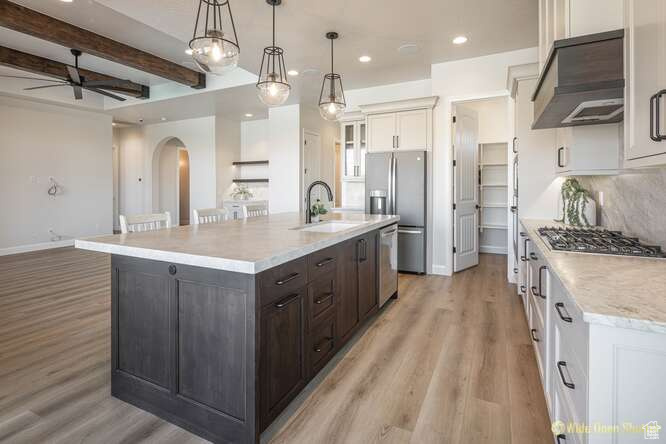 Kitchen featuring a sink, appliances with stainless steel finishes, ventilation hood, arched walkways, and a ceiling fan