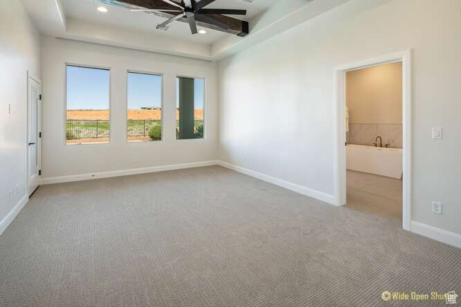 Carpeted spare room with a ceiling fan, baseboards, a tray ceiling, and recessed lighting