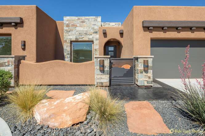 Pueblo-style home with a gate, stucco siding, and a fenced front yard