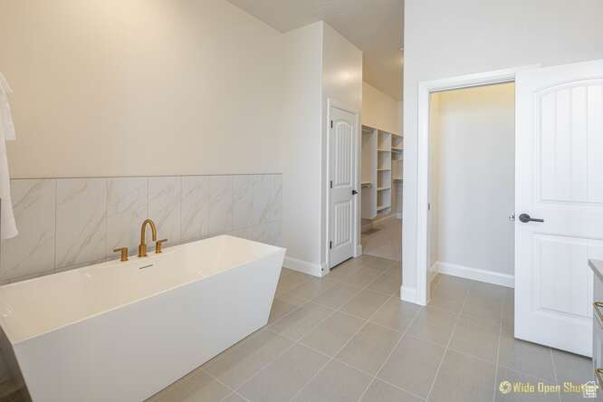 Full bathroom featuring a freestanding bath, tile patterned floors, and baseboards