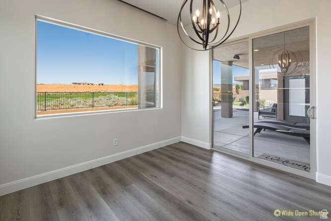 Unfurnished dining area featuring a chandelier, baseboards, and wood finished floors