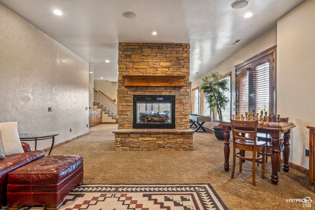Carpeted living room featuring recessed lighting, a stone fireplace, and baseboards
