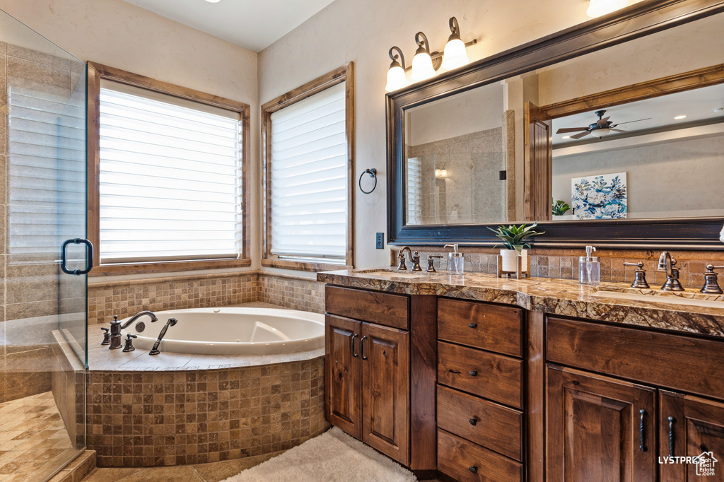 Full bath with double vanity, a garden tub, a ceiling fan, and an enclosed shower