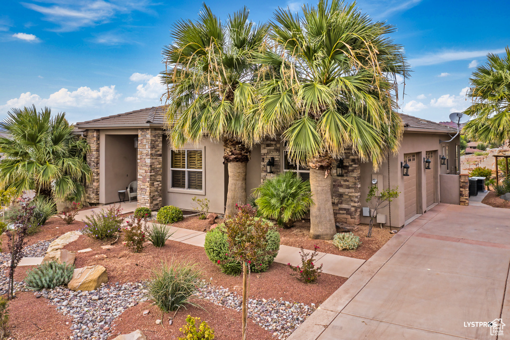 View of front of home featuring stucco siding, concrete driveway, and a garage