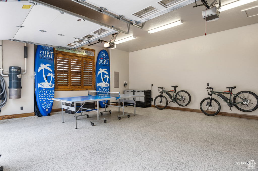 Garage featuring a garage door opener, electric panel, and baseboards