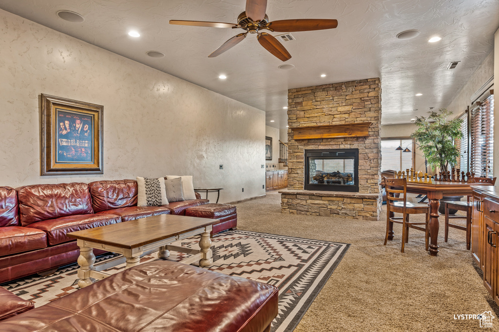 Living area with carpet floors, a ceiling fan, a fireplace, recessed lighting, and a textured wall