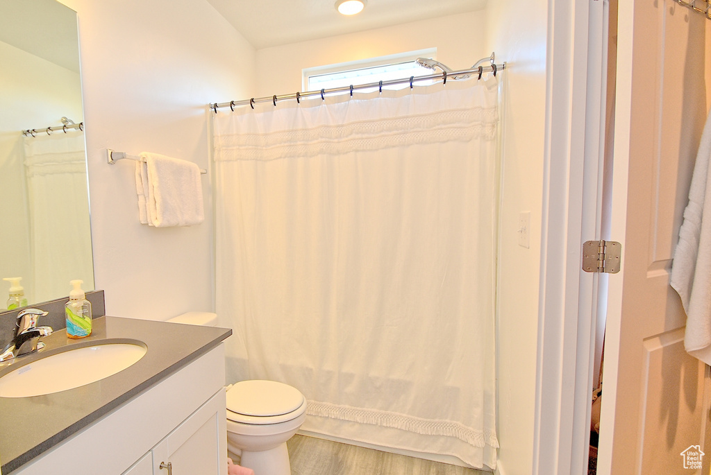Bathroom featuring toilet, vanity, wood finished floors, and shower / bath combo