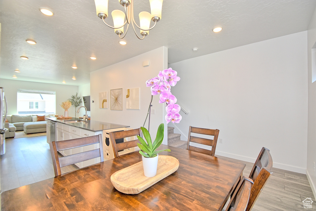 Dining area featuring stairway, light wood finished floors, recessed lighting, a chandelier, and baseboards