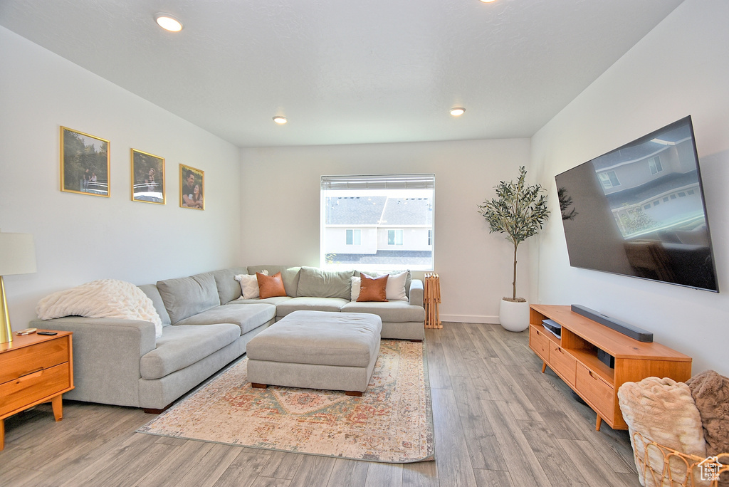 Living room with light wood-type flooring and recessed lighting