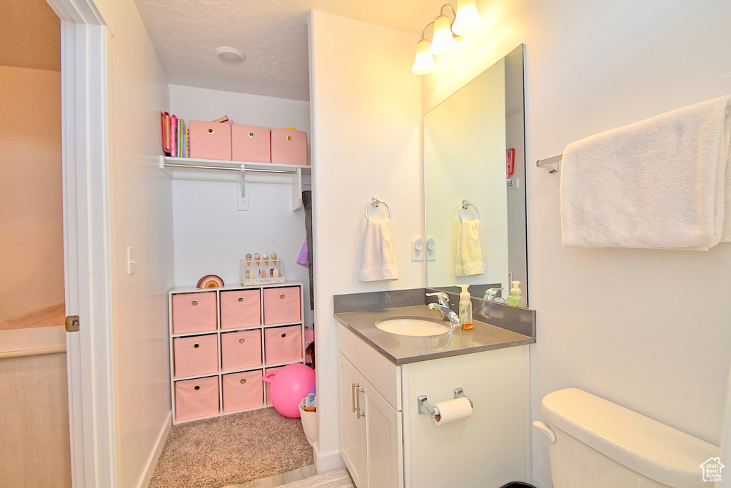 Bathroom featuring vanity, toilet, and baseboards