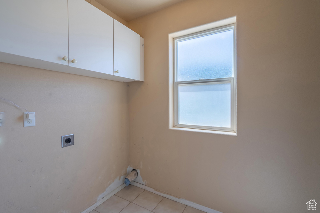 Laundry room featuring hookup for an electric dryer, cabinet space, light tile patterned floors, and baseboards