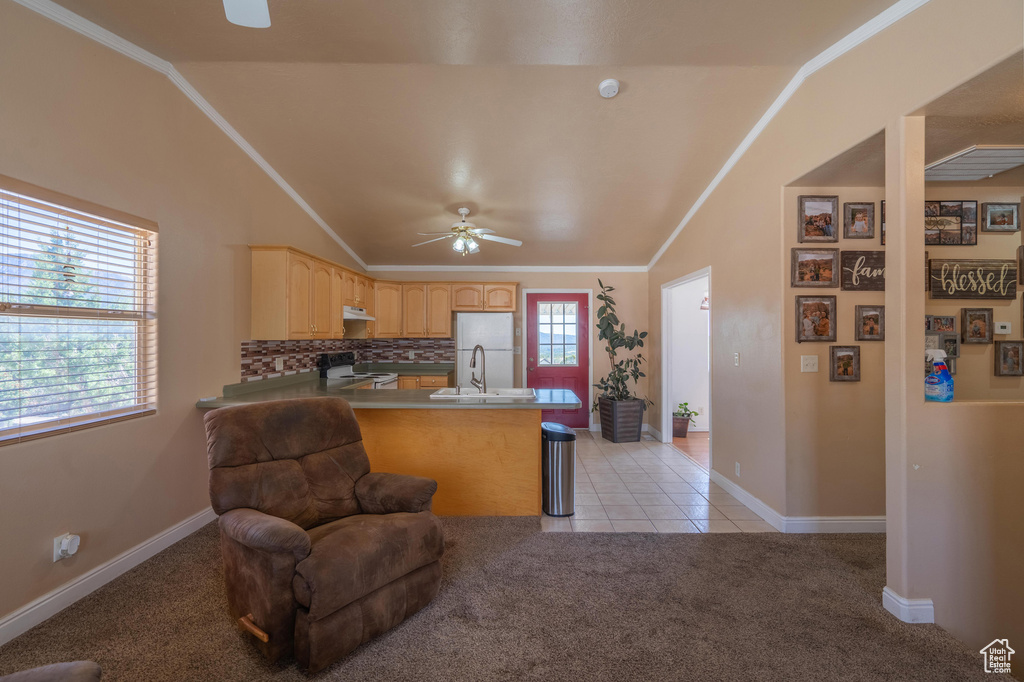 Kitchen featuring range with electric cooktop, a ceiling fan, light brown cabinets, a peninsula, and light colored carpet