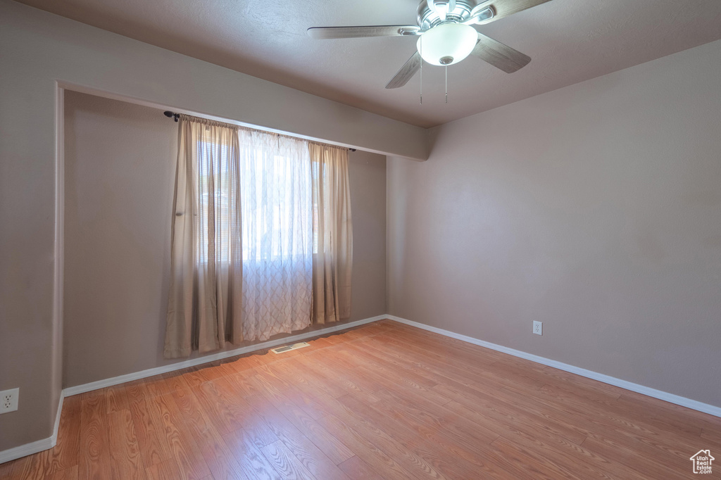 Empty room featuring light wood finished floors, baseboards, and a ceiling fan