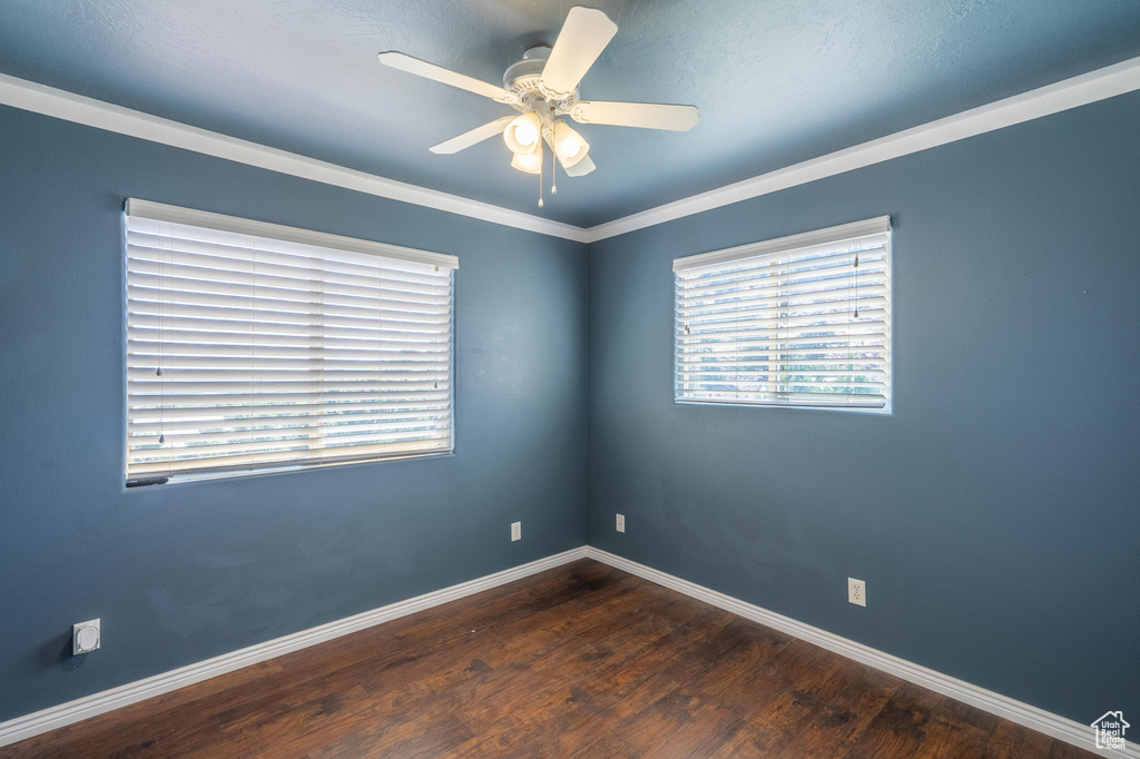 Empty room featuring wood finished floors, baseboards, a ceiling fan, and ornamental molding