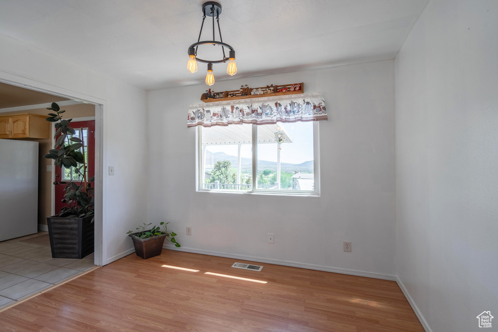 Unfurnished dining area featuring light wood finished floors and baseboards