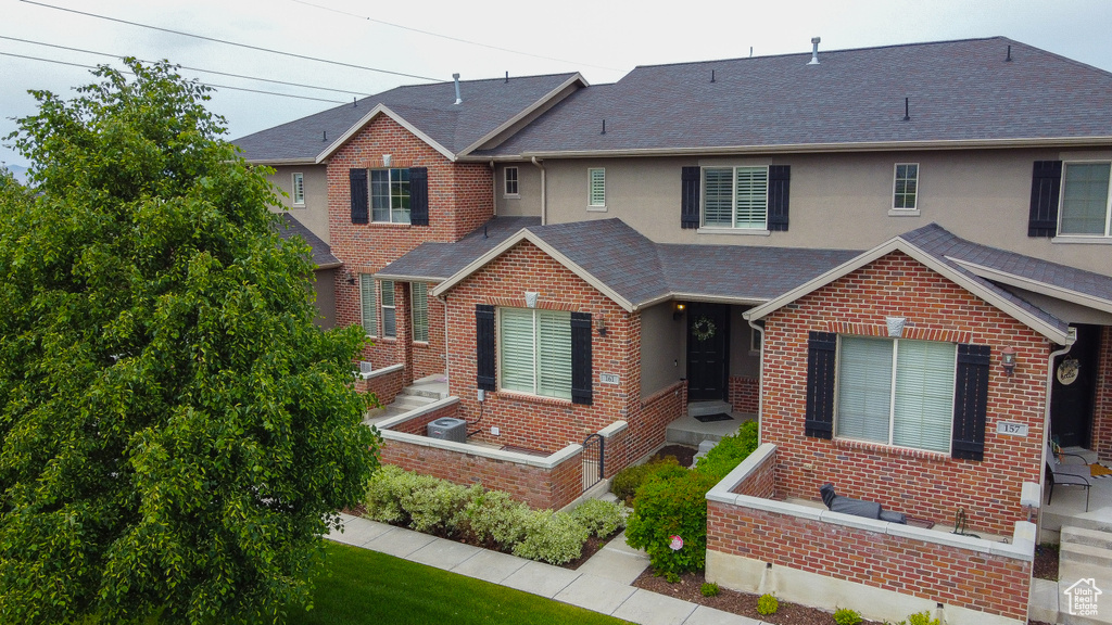 View of front of house with brick siding, a shingled roof, and stucco siding