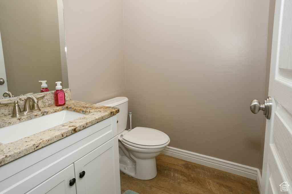 Bathroom with wood finished floors, toilet, vanity, and baseboards