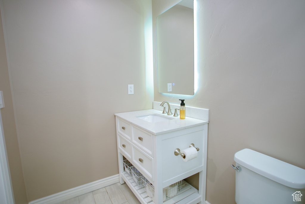Bathroom featuring toilet, vanity, and baseboards