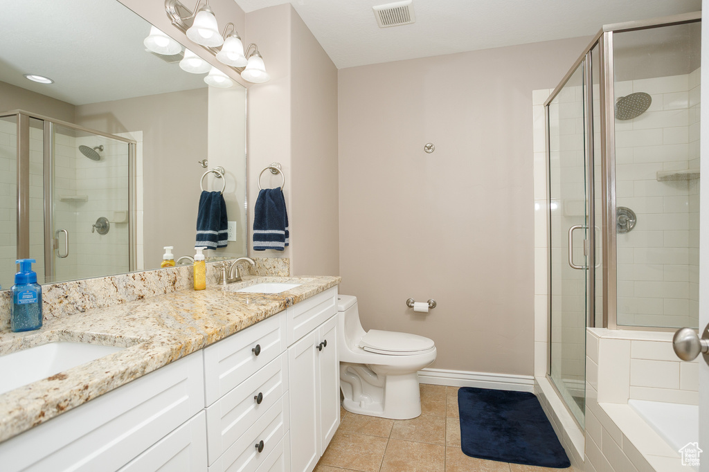 Bathroom featuring tile patterned flooring, a shower stall, toilet, double vanity, and baseboards