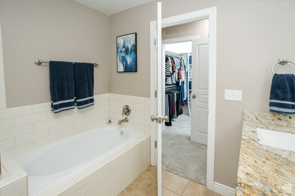 Bathroom with a walk in closet, a garden tub, and tile patterned floors