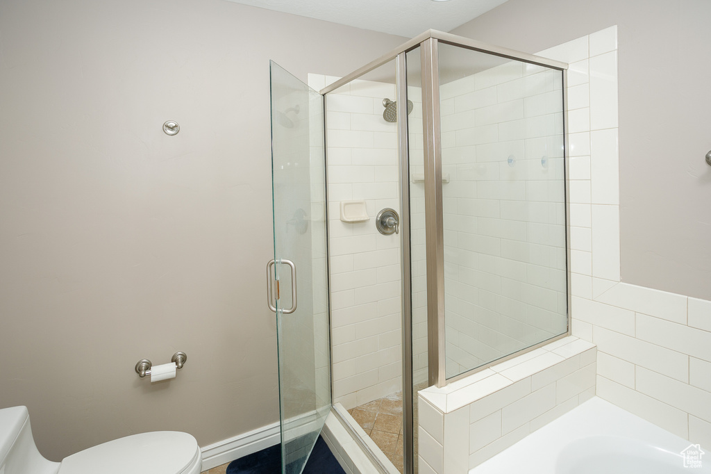 Full bathroom featuring toilet, a shower stall, and a bath