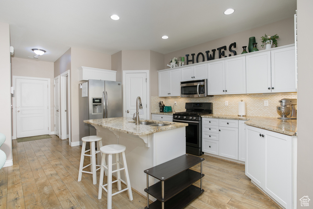 Kitchen with stainless steel appliances, a sink, backsplash, white cabinets, and recessed lighting