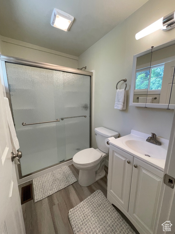 Full bath with wood finished floors, a shower stall, toilet, and vanity