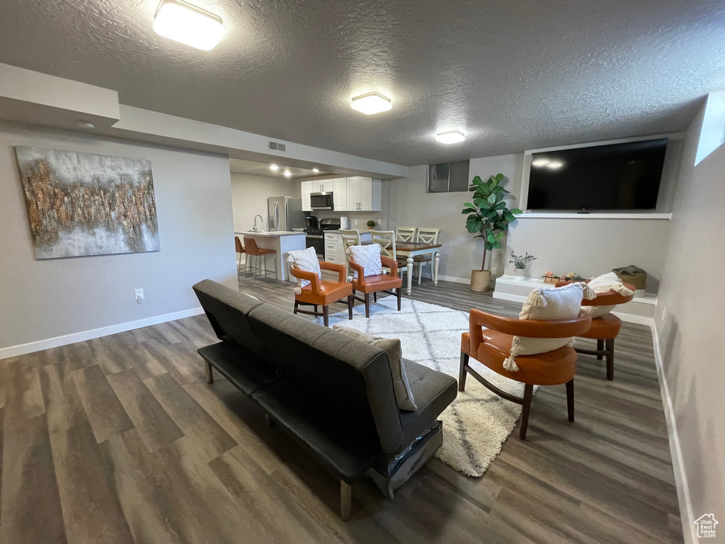 Living room featuring a textured ceiling, baseboards, and wood finished floors