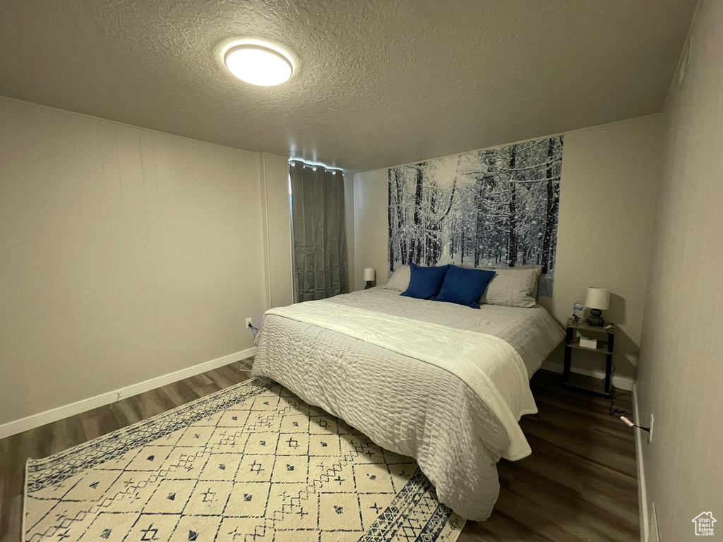 Bedroom featuring wood finished floors, a textured ceiling, and baseboards