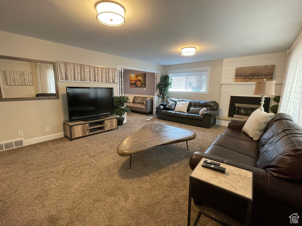 Carpeted living area featuring a fireplace and baseboards