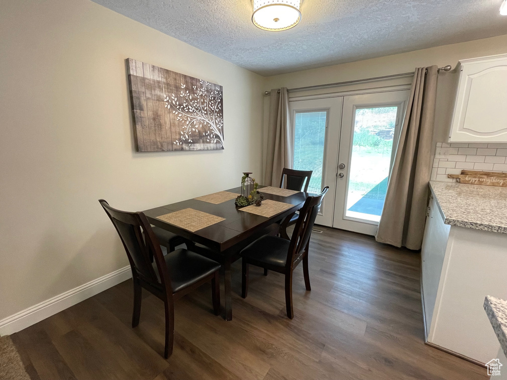 Dining space with dark wood-style floors, a textured ceiling, french doors, and baseboards