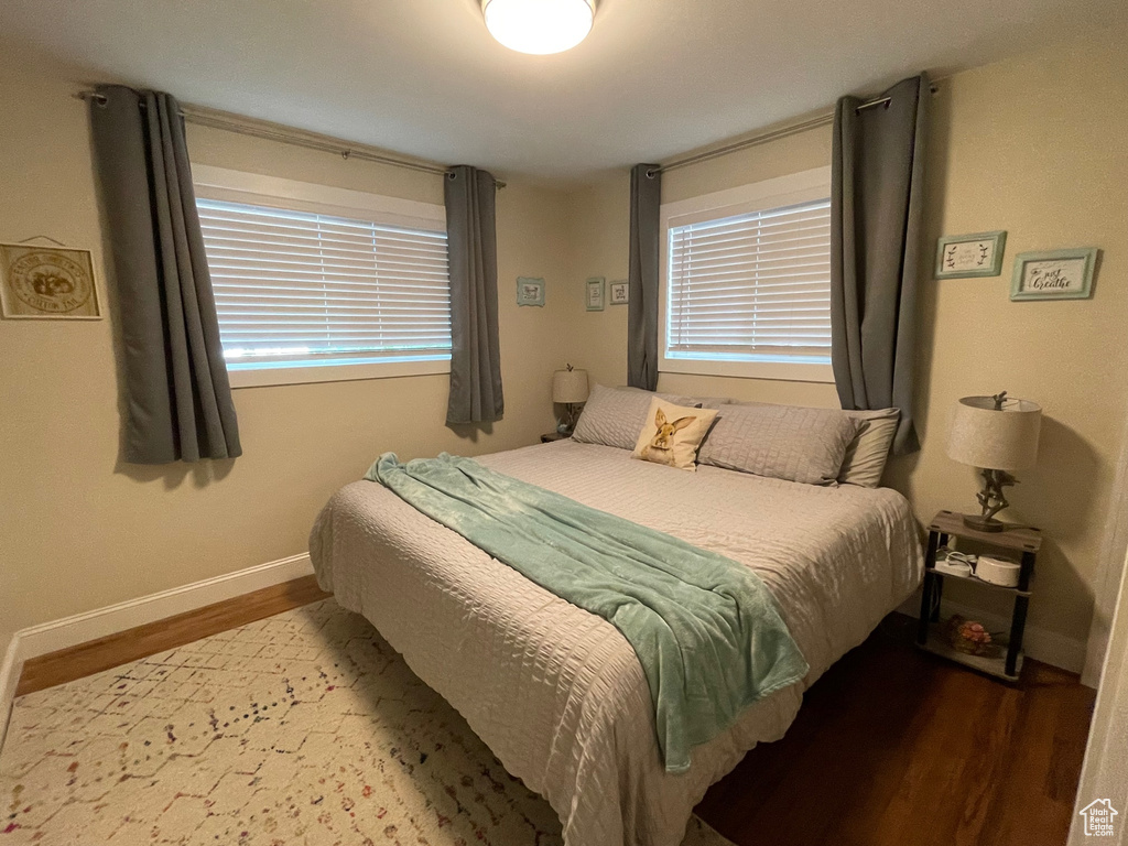 Bedroom with wood finished floors, baseboards, and multiple windows