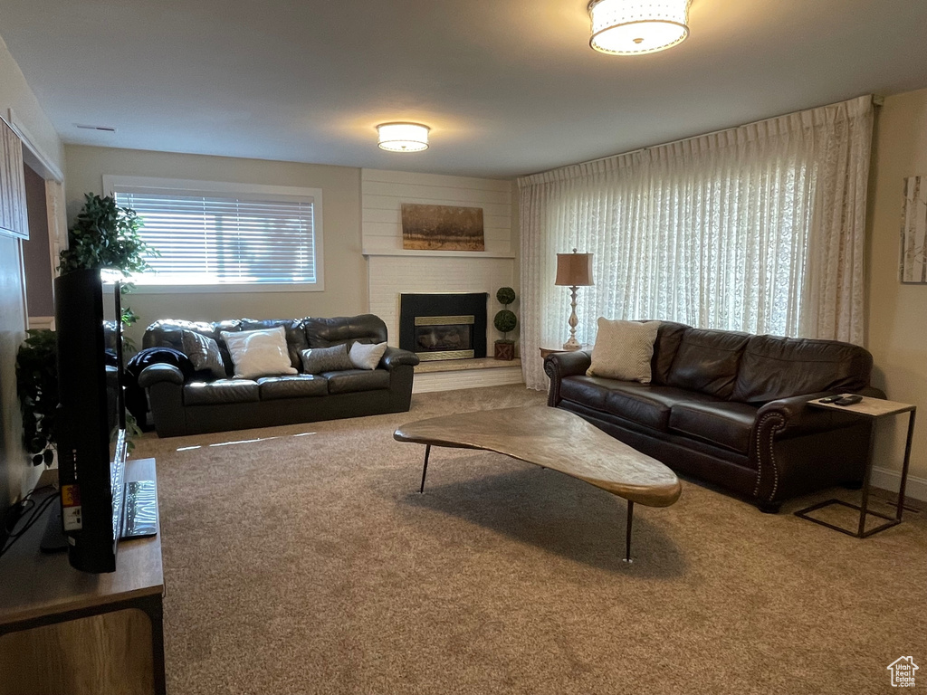 Carpeted living area featuring a brick fireplace