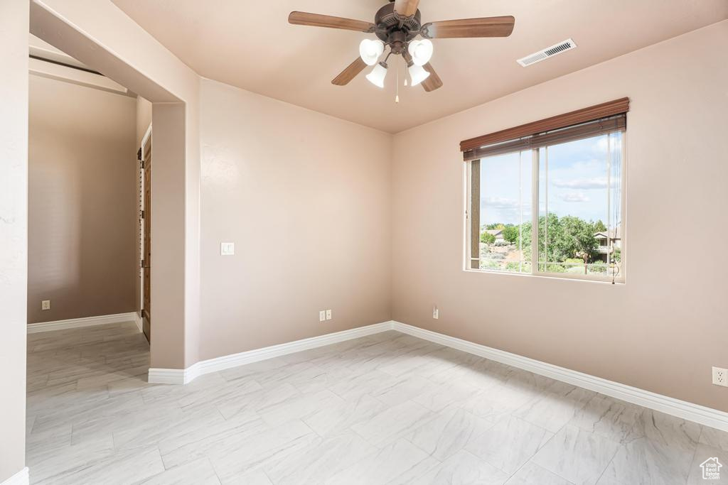 Empty room with a ceiling fan, light marble finish floors, and baseboards
