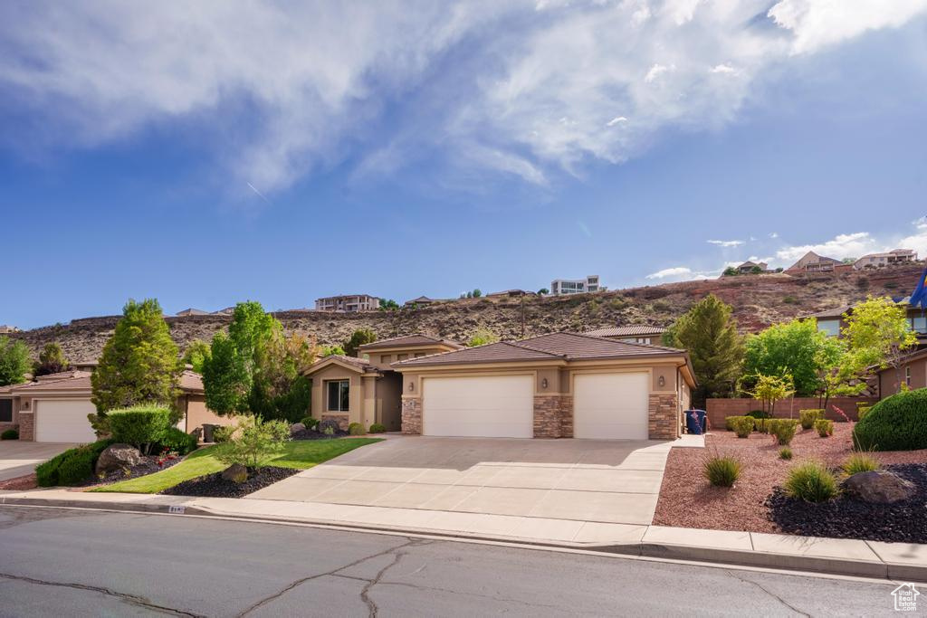 Prairie-style house featuring an attached garage, driveway, stone siding, and stucco siding
