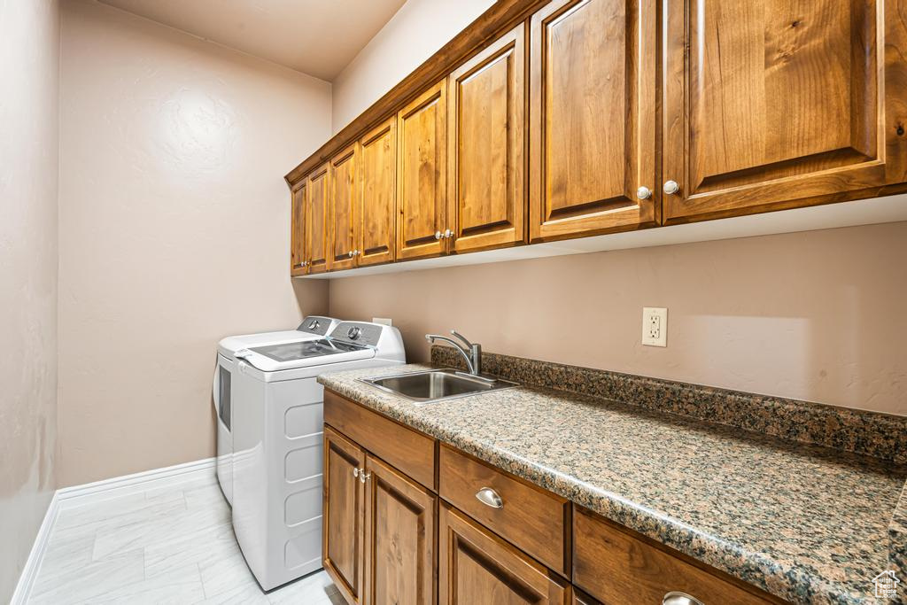 Washroom featuring independent washer and dryer, cabinet space, baseboards, and light marble finish flooring