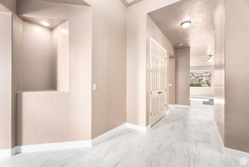 Hallway with marble look tiles and baseboards