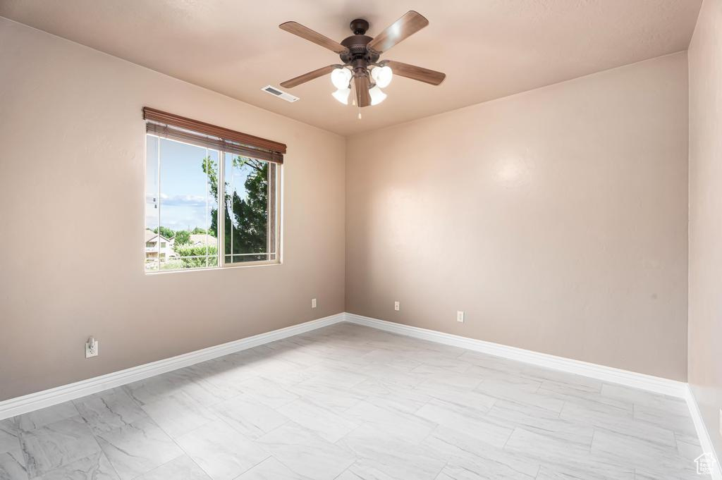 Spare room with light marble finish floors, ceiling fan, and baseboards