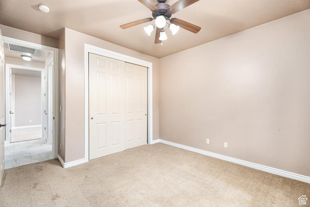 Unfurnished bedroom with carpet, baseboards, a closet, and ceiling fan