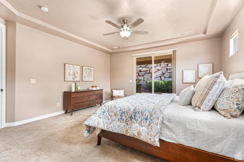 Bedroom featuring a tray ceiling, access to outside, carpet floors, baseboards, and ceiling fan