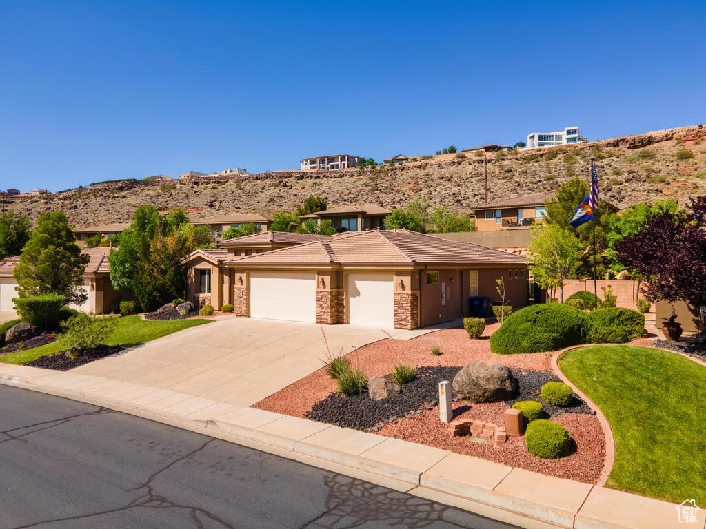View of front of house featuring an attached garage, concrete driveway, stucco siding, a tiled roof, and stone siding