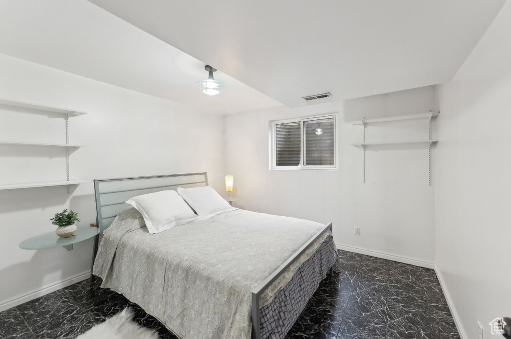 Bedroom featuring dark marble finish flooring and baseboards
